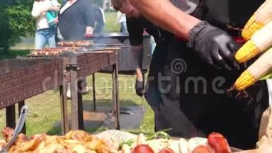 街头<strong>美食节</strong>。 一位穿着黑色衣服和手套的厨师把油炸食品铺在盘子上。 土豆，烤香肠，肉